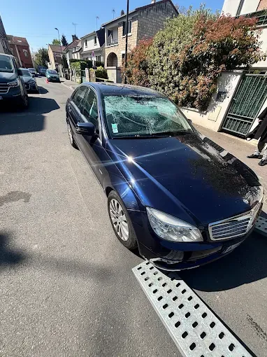 Mercedes bleue au pare-brise brisé après un accident, prise en charge par la dépanneuse