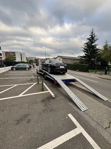 Plateau de dépanneuse rampes baissées pour charger une voiture sur un parking