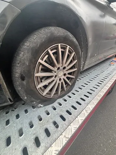 Gros plan sur un pneu crevé, à plat, sur le plateau de la dépanneuse