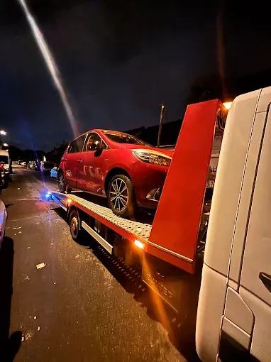 Renault Clio rouge chargée de nuit sur la dépanneuse, gyrophares allumés