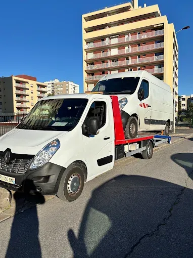 Dépanneuse transportant un véhicule utilitaire blanc
