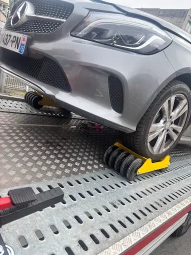 Mercedes grise à l'avant endommagé, roue calée sur le plateau de la dépanneuse