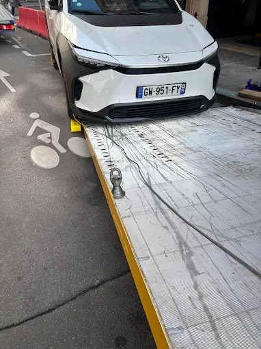 Toyota électrique blanche montée sur le plateau de la dépanneuse, en bord de piste cyclable