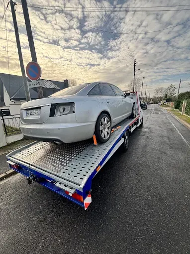 Audi A6 grise arrimée sur un plateau porte-voiture pour un transport